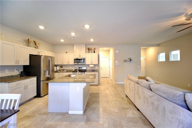 kitchen with white cabinets, stainless steel appliances, dark stone counters, and sink