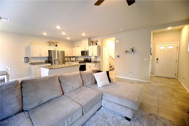 living room featuring light tile patterned floors, ceiling fan, and sink