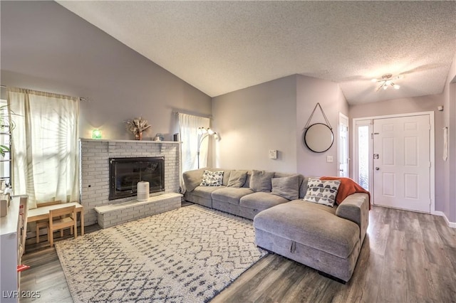 living room featuring lofted ceiling, a fireplace, a textured ceiling, and hardwood / wood-style flooring