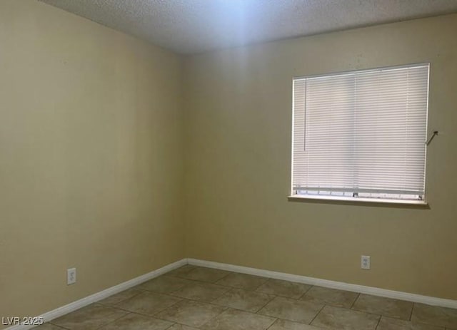 tiled empty room featuring a textured ceiling