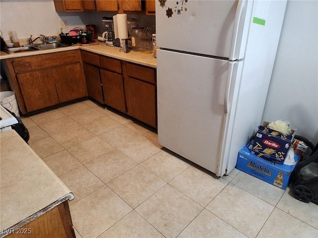 kitchen with white fridge, light tile patterned floors, and sink