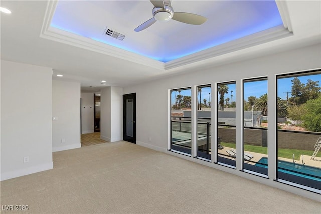 carpeted spare room featuring a raised ceiling and ceiling fan