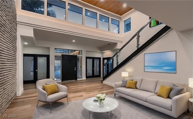 living room with wood finished floors, stairs, wood ceiling, french doors, and a towering ceiling