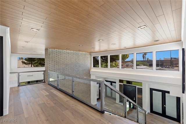 hallway featuring hardwood / wood-style flooring, brick wall, and wood ceiling