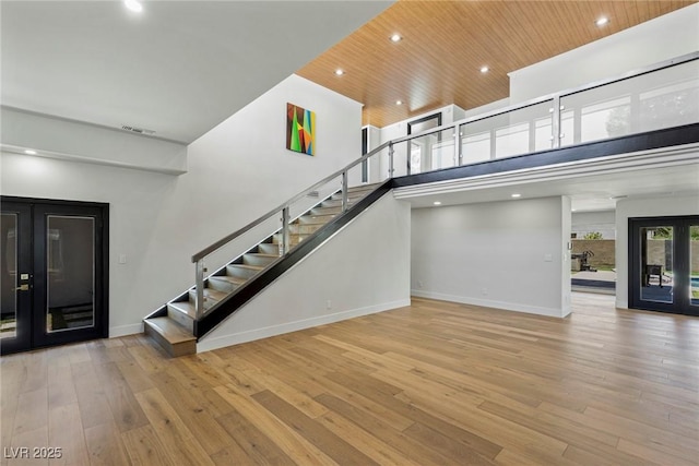 staircase with a high ceiling, hardwood / wood-style floors, wooden ceiling, and french doors