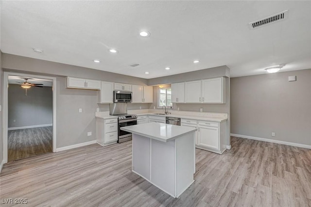 kitchen featuring white cabinetry, light hardwood / wood-style flooring, a kitchen island, and stainless steel appliances