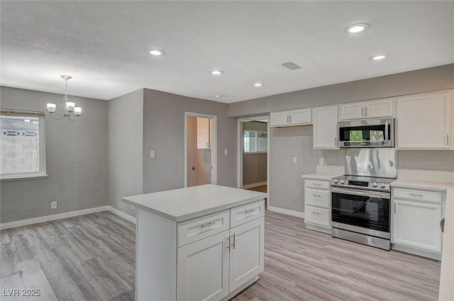 kitchen featuring white cabinetry, stainless steel appliances, hanging light fixtures, and light hardwood / wood-style flooring