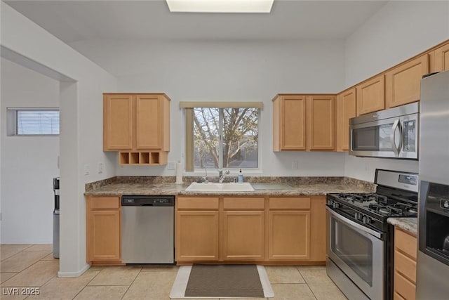 kitchen featuring appliances with stainless steel finishes, light tile patterned floors, light brown cabinetry, and sink