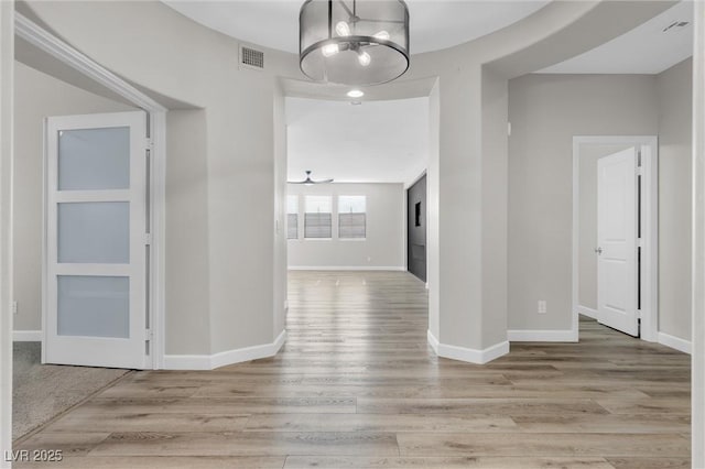 hallway featuring an inviting chandelier and light hardwood / wood-style flooring