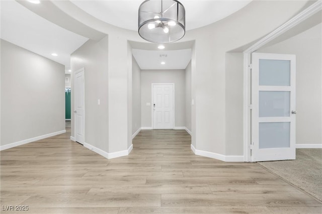 hall with a notable chandelier and light hardwood / wood-style floors