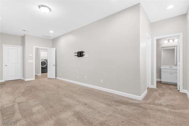 unfurnished bedroom featuring light carpet, washer / clothes dryer, and ensuite bath