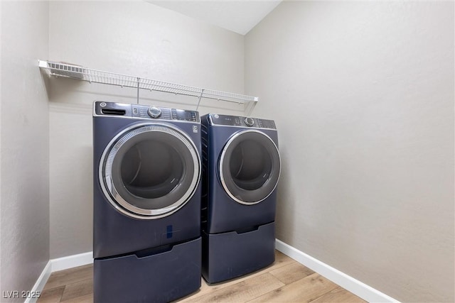 laundry room featuring washer and dryer and light hardwood / wood-style flooring