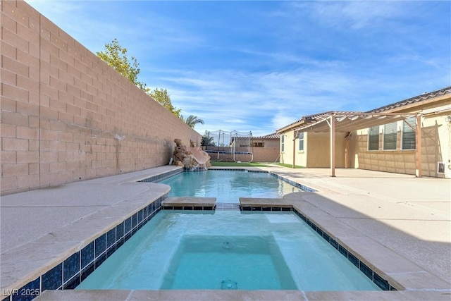 view of swimming pool with a trampoline and an in ground hot tub