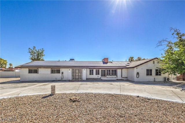 ranch-style home with solar panels and a patio area