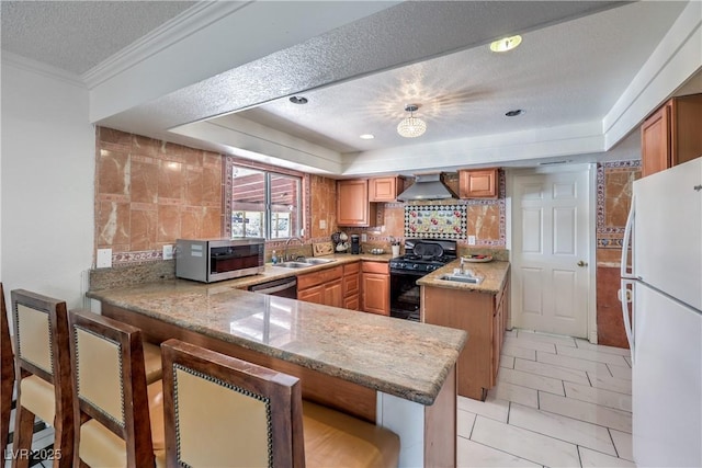 kitchen featuring sink, wall chimney range hood, kitchen peninsula, a textured ceiling, and appliances with stainless steel finishes