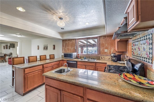 kitchen featuring a kitchen breakfast bar, a textured ceiling, stainless steel appliances, and sink