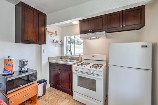 kitchen with dark brown cabinetry, sink, light tile patterned flooring, and white appliances