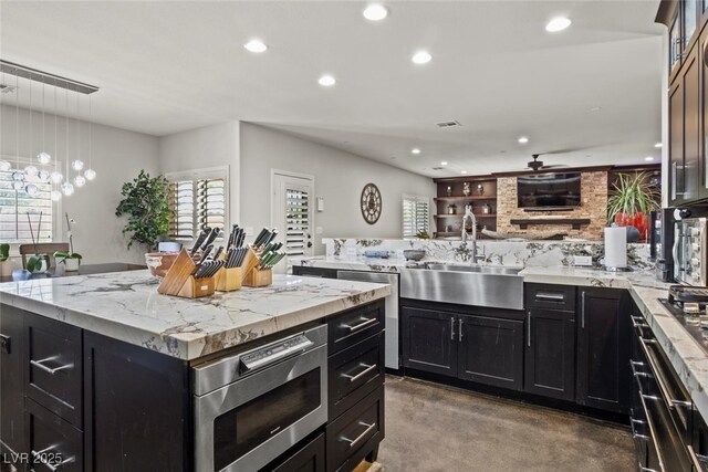 kitchen featuring recessed lighting, a peninsula, a sink, and dark cabinetry