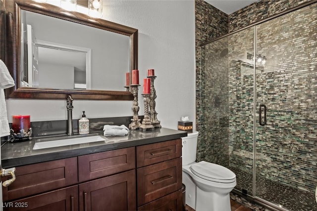 full bathroom featuring vanity, a stall shower, and toilet