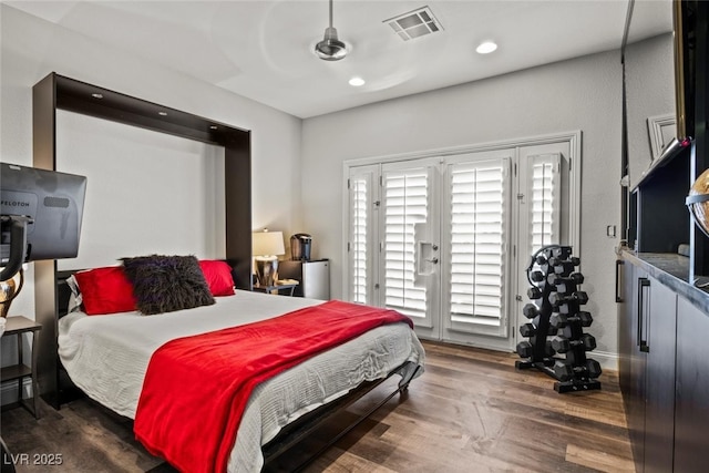 bedroom featuring access to exterior, wood finished floors, multiple windows, and visible vents