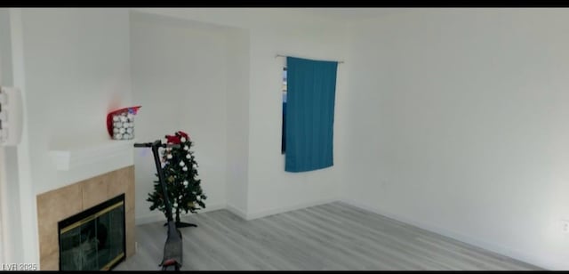 exercise room with a tile fireplace and light wood-type flooring