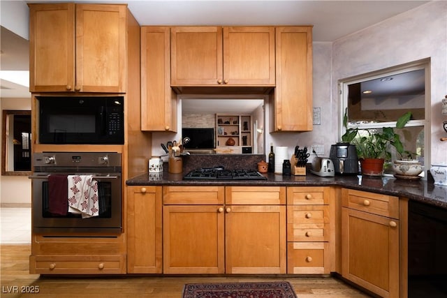 kitchen featuring light hardwood / wood-style flooring, dark stone counters, and black appliances