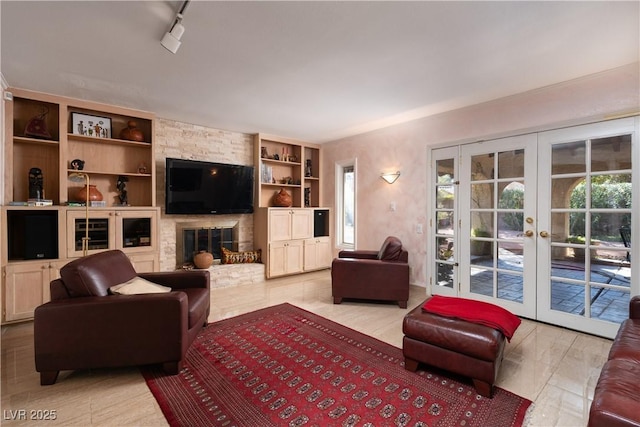 living room featuring a fireplace, french doors, and rail lighting