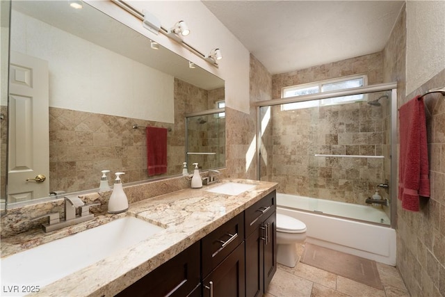 full bathroom with vanity, toilet, tile walls, and enclosed tub / shower combo