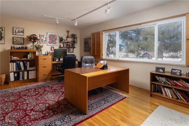 home office with rail lighting and light hardwood / wood-style floors