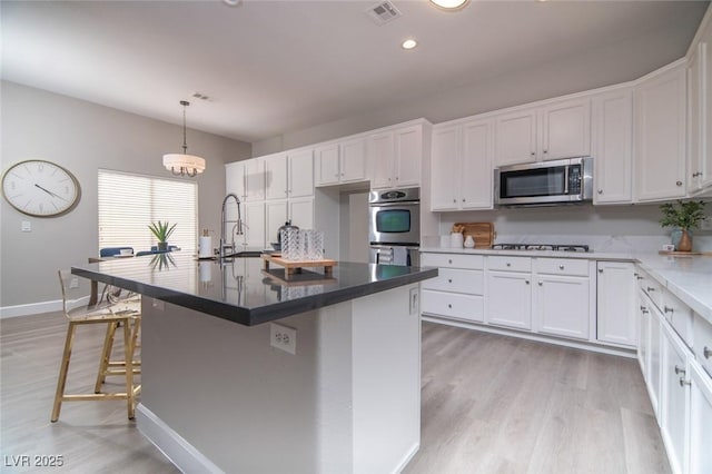 kitchen with white cabinetry, an island with sink, and stainless steel appliances