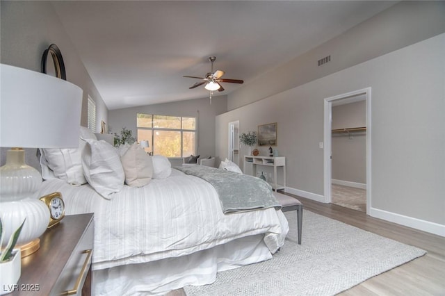 bedroom featuring ceiling fan, hardwood / wood-style floors, lofted ceiling, a walk in closet, and a closet