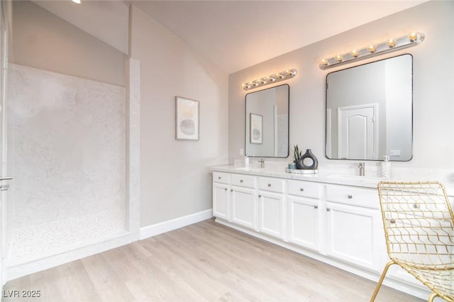 bathroom with a shower, hardwood / wood-style floors, vanity, and vaulted ceiling