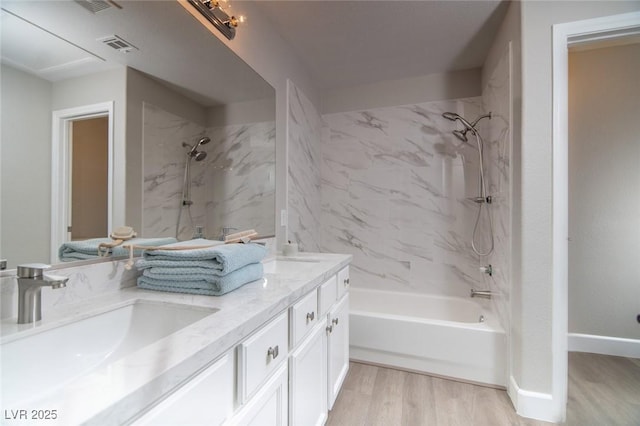 bathroom with wood-type flooring, vanity, and tiled shower / bath combo