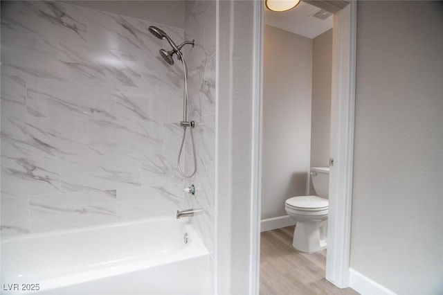 bathroom featuring toilet, tiled shower / bath, and hardwood / wood-style flooring