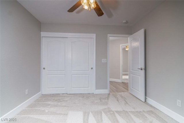 unfurnished bedroom featuring ceiling fan, a closet, and light carpet