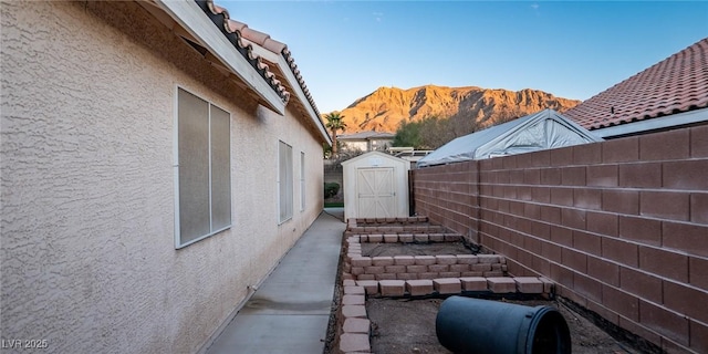 view of home's exterior with a mountain view and a storage unit