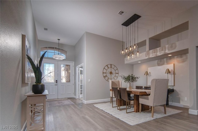 entrance foyer with wood-type flooring, a high ceiling, and french doors