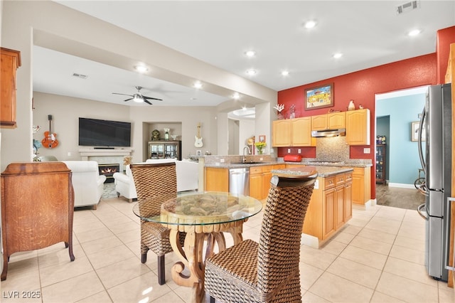 kitchen with kitchen peninsula, appliances with stainless steel finishes, ceiling fan, sink, and light tile patterned flooring