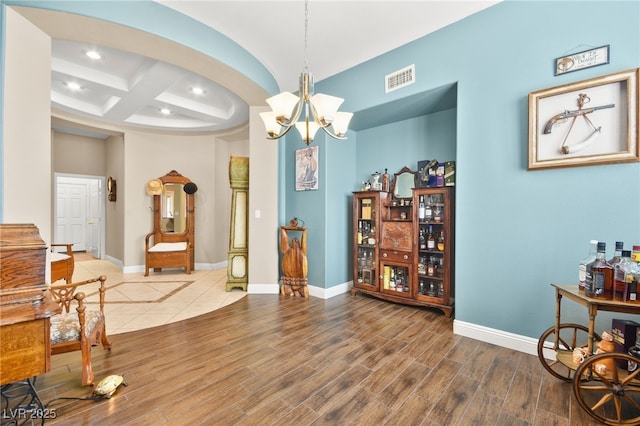 sitting room featuring beamed ceiling, coffered ceiling, and a notable chandelier