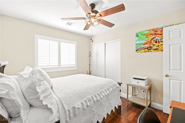 bedroom with ceiling fan, dark wood-type flooring, and a closet