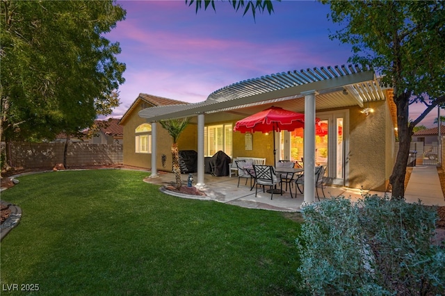 back house at dusk with a lawn and a patio