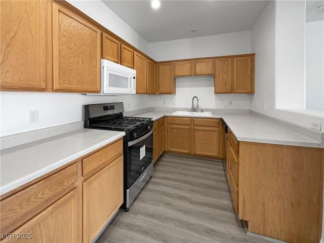 kitchen featuring gas range, sink, and light wood-type flooring