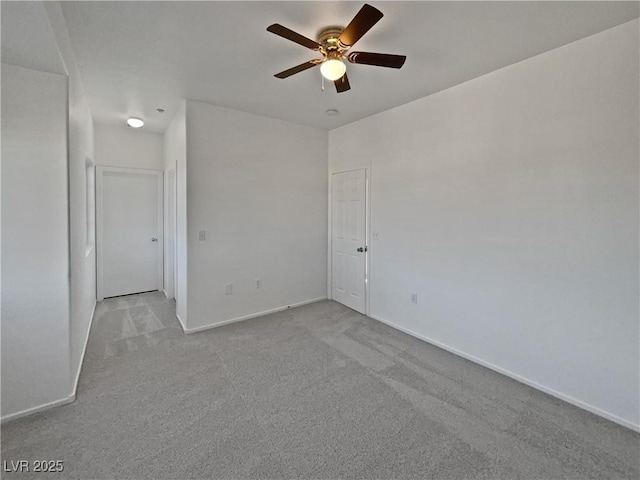 empty room featuring ceiling fan and light colored carpet