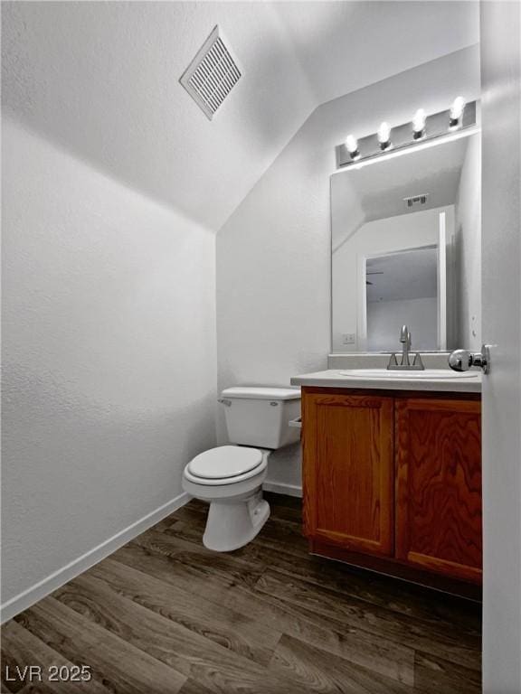 bathroom with hardwood / wood-style floors, vanity, toilet, and vaulted ceiling