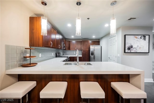 kitchen with a breakfast bar, appliances with stainless steel finishes, kitchen peninsula, and sink