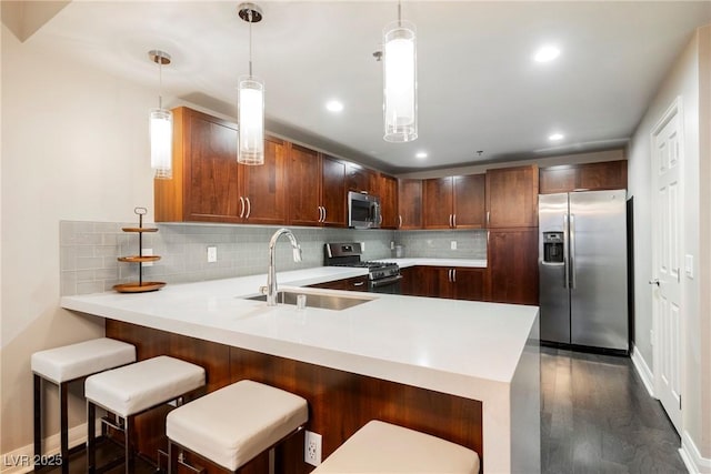 kitchen featuring kitchen peninsula, appliances with stainless steel finishes, decorative light fixtures, and sink