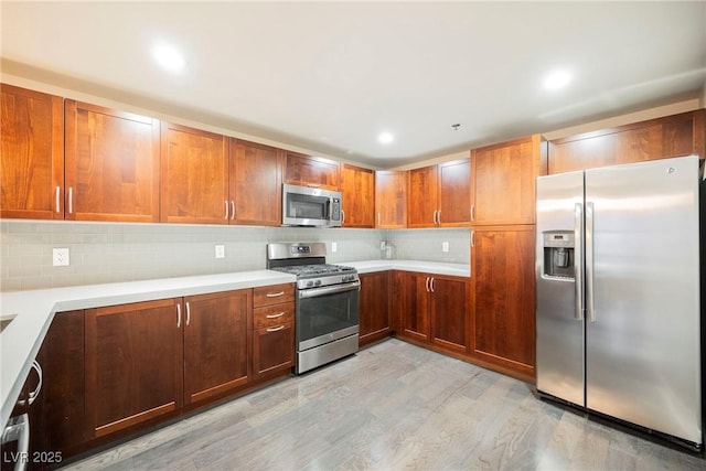 kitchen with tasteful backsplash, appliances with stainless steel finishes, and light hardwood / wood-style flooring