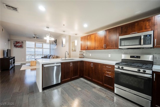 kitchen featuring ceiling fan, sink, hanging light fixtures, kitchen peninsula, and appliances with stainless steel finishes