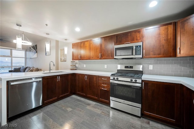 kitchen with sink, hanging light fixtures, stainless steel appliances, dark hardwood / wood-style floors, and decorative backsplash