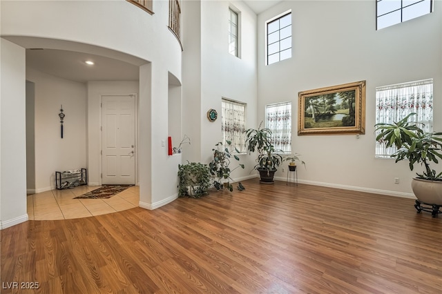 foyer entrance with light wood-type flooring, a high ceiling, and a wealth of natural light